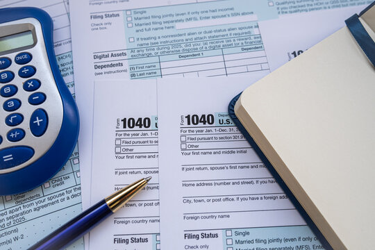 Close up of Accountant Desk with Form 1040 Tax Documents Blue Calculator and Blank Notepad