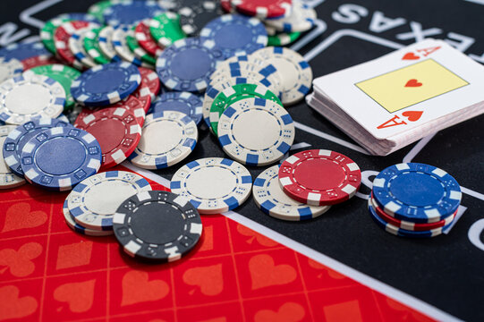 Top View of Scattered Poker Tokens and Playing Cards Deck on Black Casino Table Layout