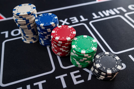 Rows of Colorful Casino Poker Chips Stacked on Black Gaming Table for High Stakes Gambling