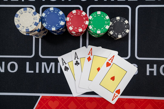Close up of Four Aces Cards Spread Near Stacked Poker Tokens on Black Gaming Table Surface