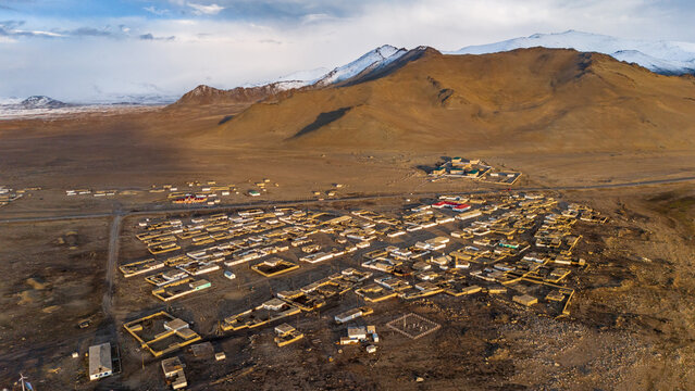 Aerial view of the village of Chah Ab near Karakul Lake, featuring traditional low-rise dwellings and arid mountain terrain in Chah Ab, Gorno-Badakhshan, Tajikistan.