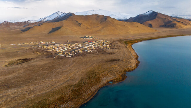 Aerial view of Karakul Lake with its turquoise waters set against arid plains and snow-capped mountains in Gorno-Badakhshan, Tajikistan.