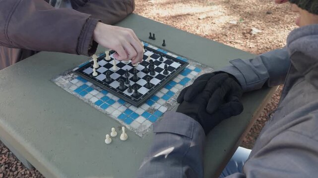 People playing chess at a park table in winter slow motion