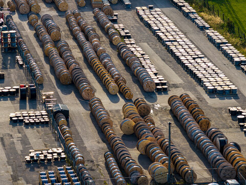 Aerial view of numerous large wooden cable reels arranged in neat rows within an industrial storage yard in Kaunas, Kaunas County, Lithuania.