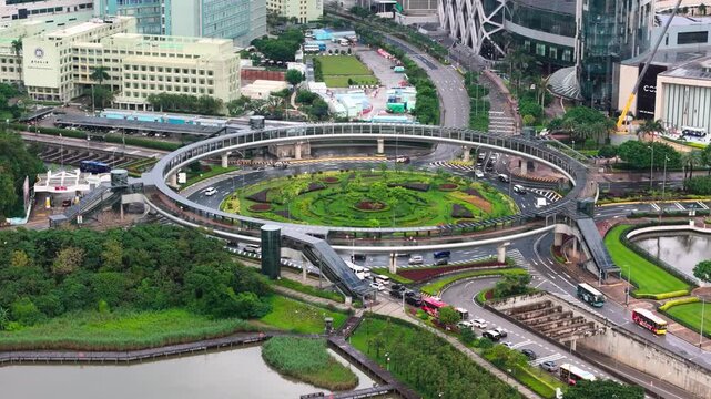 Aerial view of traffic flowing through modern circular pedestrian bridge and roundabout in Macao.