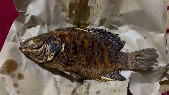 Authentic home cooked fried fish dish served on oil paper rustic style