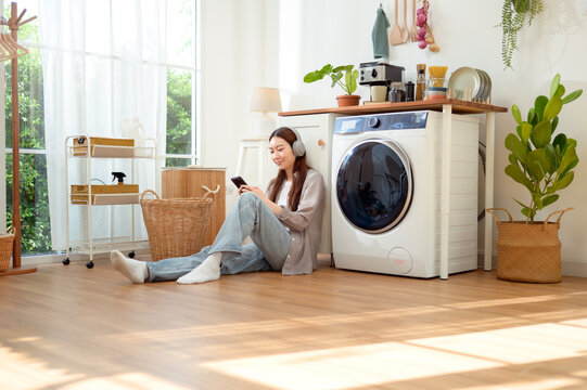 woman Listening to Music While Doing Laundry at Home in the Morning