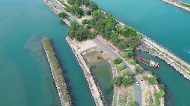 An aerial drone view of the coastal road in Ulee Lheue, Banda Aceh, leading towards the ferry port to Sabang Island, surrounded by calm sea waters and mountains.