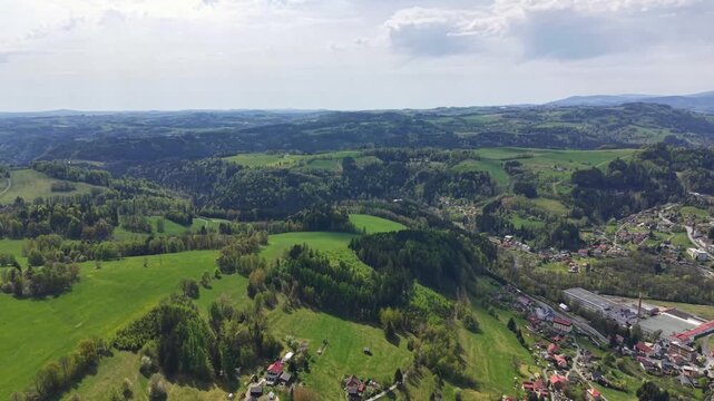 Aerial view of a rural landscape no visible action static scene, in rural countryside with green fields and distant hills, with green fields, hills, roads, buildings, with green, blue accents.