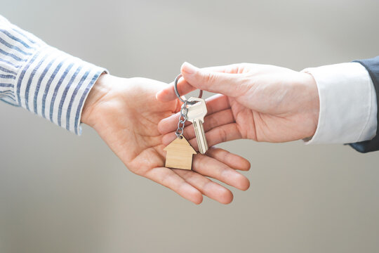 Close up agent giving a key to new owner or tenant, client after signed signature contract rental purchase, buyer apartment, home with landlord, realtor. Banker agreement mortgage loan. Property lease