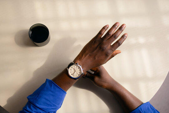 Person Checking Wristwatch While Sitting at Table