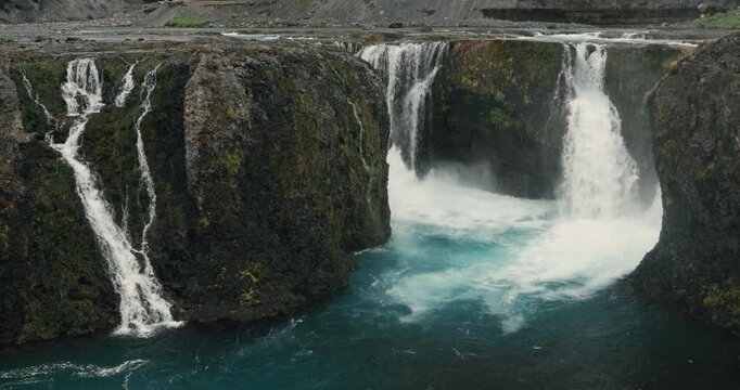 Sig&ouml;ldufoss waterfall flowing through the rugged volcanic landscape of Iceland's Highlands, with turquoise water, moss-covered rocks and multiple cascading falls creating a dramatic natural scene.