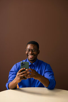 Smiling Man Using Smartphone While Sitting At Table