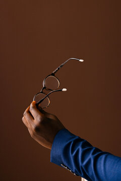 Hand Holding Glasses Over Brown Background