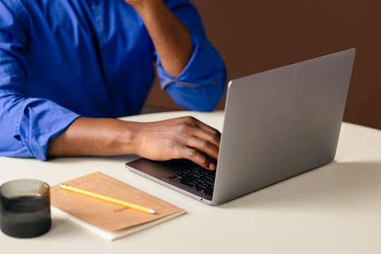 Person Working on Laptop With Notebook and Pencil