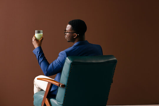 Man in Blue Blazer Holding Green Drink While Seated