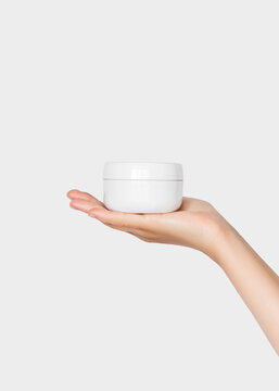 Hand holding a jar of cosmetic cream on a white background. Beauty product concept