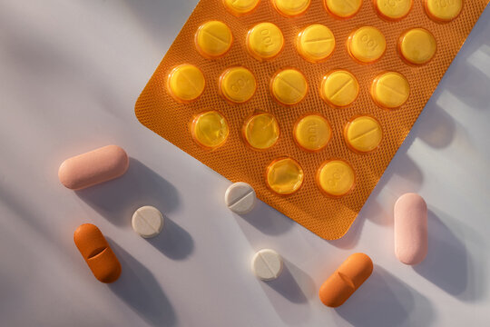 Various pills and blister pack scattered on a white surface