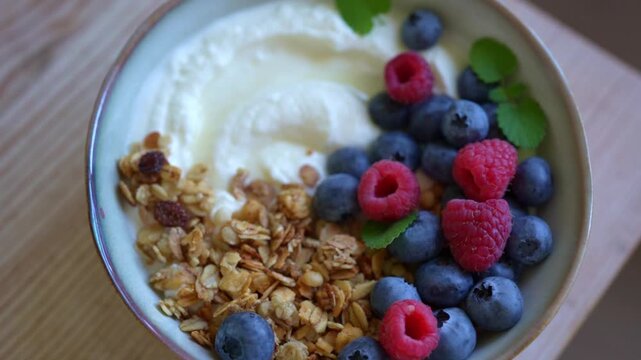 Delicious bowl of greek yogurt topped with granola and fresh berries for healthy breakfast. Granola bowl with blueberries and raspberries close up.