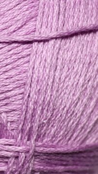 A purple ball of yarn sits on a table, awaiting use in a craft project or knitting endeavor. Rotating in a circle