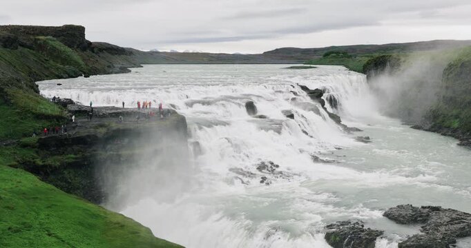 Powerful Gullfoss waterfall cascading through a dramatic canyon in southwest Iceland, with glacial water rushing over multiple rocky tiers and mist rising from the Hv&iacute;t&aacute; River.
