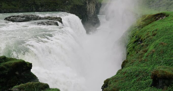 Powerful Gullfoss waterfall cascading through a dramatic canyon in southwest Iceland, with glacial water rushing over multiple rocky tiers and mist rising from the Hv&iacute;t&aacute; River.
