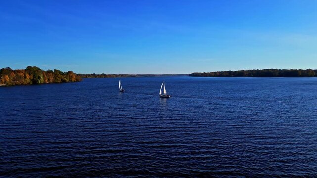Aerial view of two sailboats gliding across the blue waters of the Daugava River near the Kegums HES in Kegums, Ogres novads, Latvia.