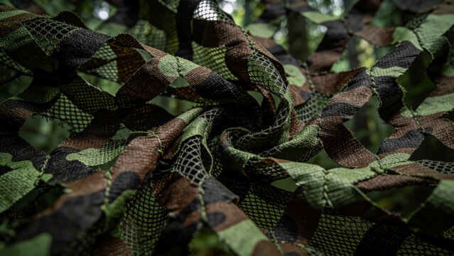 Military camouflage mesh texture background. Dark, brown and green material surface backdrop. Army style camo netting for camping, fishing and hunting. Hiding, staying safe in the forest. Copy space