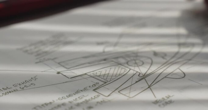 Designer places futuristic spaceship technical drawings and blueprints on a worktable as soft morning sunlight casts striped shadows across the workspace.