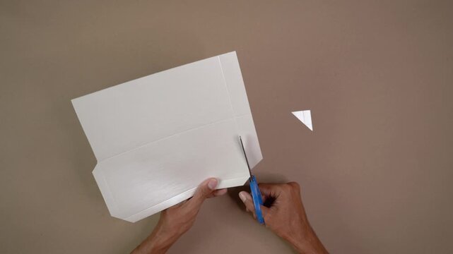 Person cutting white cardstock with scissors for DIY arts and crafts project creating envelope