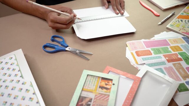 Craftsperson's hands measuring and drawing on paper for creative handmade window envelope