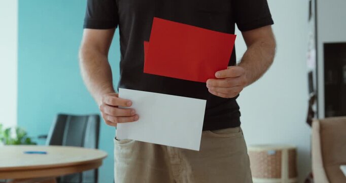 Person holding a red envelope and letter at home, representing an official warning, overdue payment notice, debt collection or important notification.