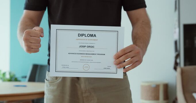 Person proudly holding a diploma certificate after successful graduation, representing education, achievement, qualification, success and career development.