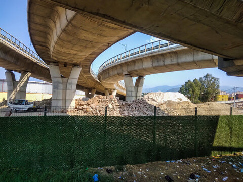 Concrete highway overpass infrastructure crossing urban landscapes with bright blue skies seen from a low perspective during a sunny day with natural light and sharp shadows