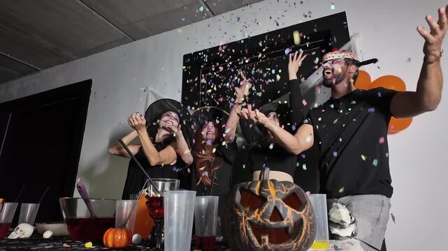Friends in Halloween costumes celebrate by throwing confetti into the air