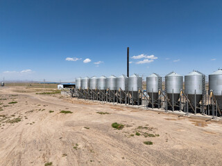 silver grain silos for agricultural storage under blue sky © zhu difeng
