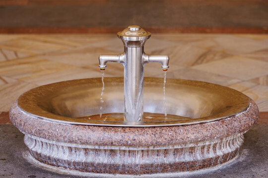 Elegant stone drinking fountain with dual steel taps in public space
