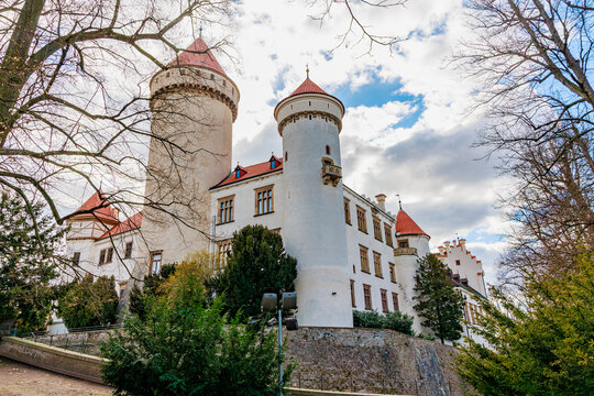 Medieval european castle with red towers surrounded by trees on a cloudy day