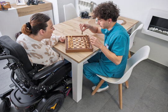 Caregiver and disabled woman playing intellectual chess game