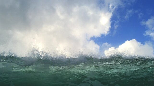 Ocean swell rolling beneath towering white clouds and blue sky in extended slow motion