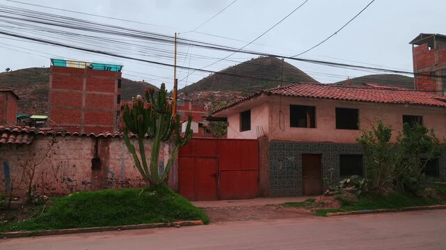 Cusco City of Cuzco mi casa local Peruvian neighborhood home building structure red fence entrance Peru landscape Anta Province Sacred Valley rainy season cloudy morning power cable lines static