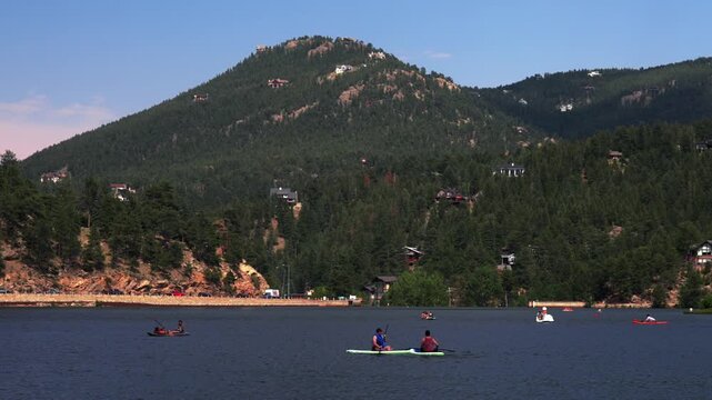 Paddleboarding summer Evergreen Lake water sport activities landscape downtown Evergreen Colorado aerial drone pan left boats Main Street downtown morning sunny clouds blue sky static shot