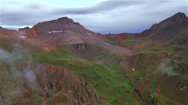 Yankee Boy Basin high alpine Mount Sneffels Ridgway Telluride Ouray Southern Colorado aerial drone view 4x4 AWD dirt road summer rainy low cloudy afternoon Rocky Mountains San Juan Range landscape pan