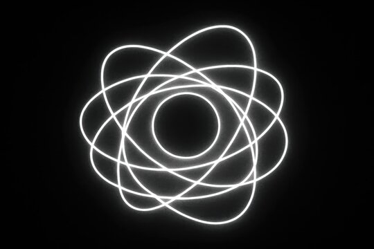 Glowing white atomic model symbol with intersecting orbital rings around a central nucleus on black background