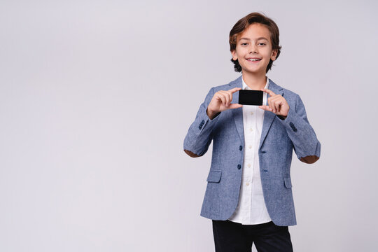 Happy male child in formal outfit holding credit card isolated on grey background, childhood, finance, payment, shopping, future businessman and money concept