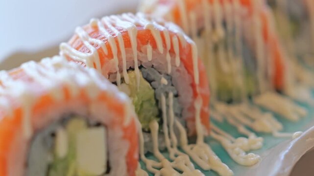 Smooth camera pan across beautifully arranged salmon sushi rolls, highlighting fresh ingredients, vibrant colors, and elegant Japanese food presentation.