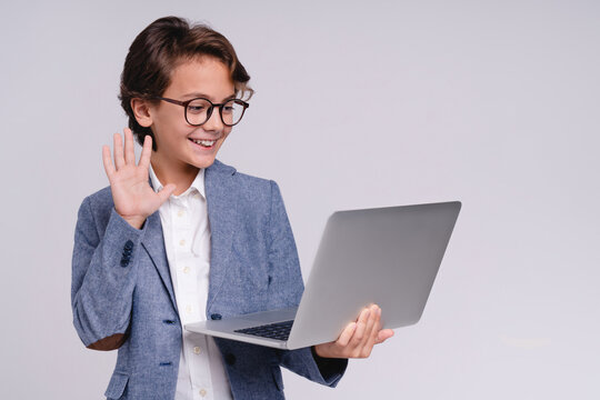 Small male kid having a video call on laptop isolated on grey background, childhood, technology, communication, online learning, remote education and lifestyle concept
