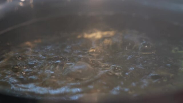 Close-up of a steaming shabu shabu hot pot with vigorously bubbling broth, rising steam, and a rich savory soup base ready for cooking.