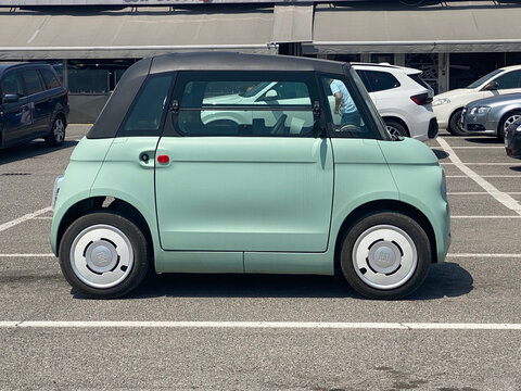 Fiat Topolino electric urban mobility microcar in mint green parked on asphalt lot, future of city transportation