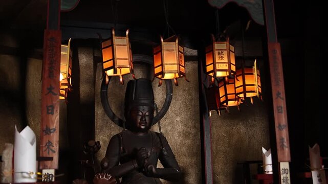 Warm lantern light surrounds a seated Buddhist statue inside Ryozen Kannon, creating an intimate scene of prayer, remembrance and spiritual devotion in Kyoto&rsquo;s Higashiyama district